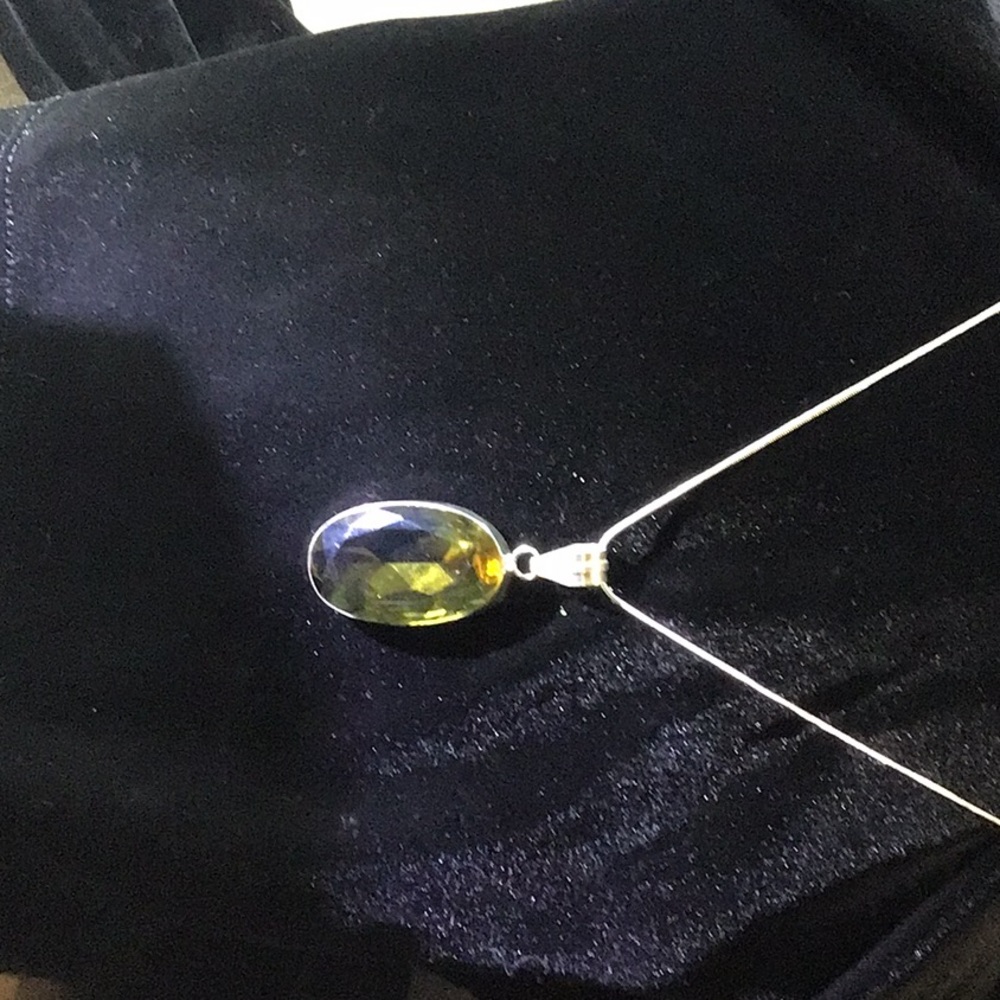 Clear slightly yellow crystal.  Silver 18 inch neckless and rim.